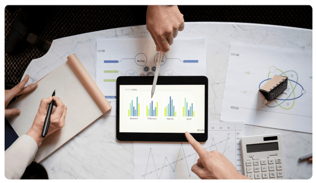 Hands pointing at a tablet displaying financial bar charts
