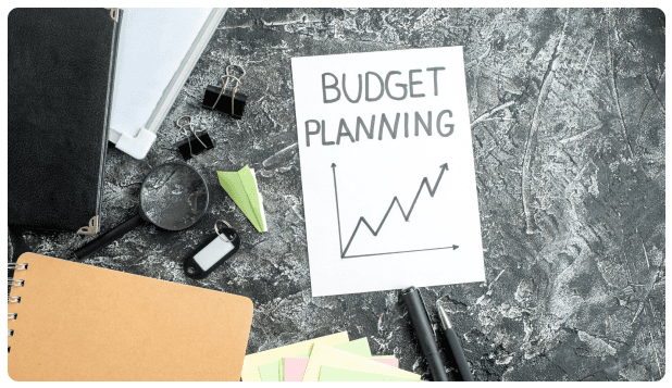 Note card reading Budget Planning next to an upward trending chart