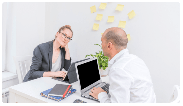 Two advisors discussing financial strategy at a desk with laptops