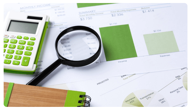 Calculator and magnifying glass over financial income and expense charts