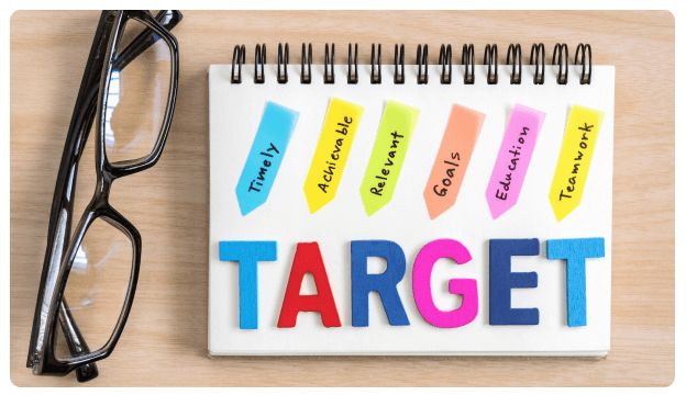 Sticky notes spelling out target goals on a notepad beside a pair of glasses