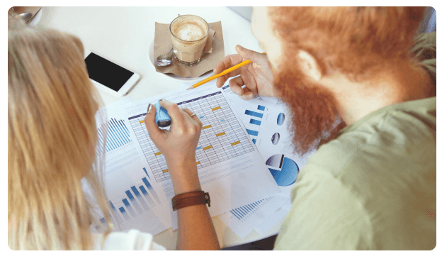 Team reviewing printed financial charts and graphs over coffee