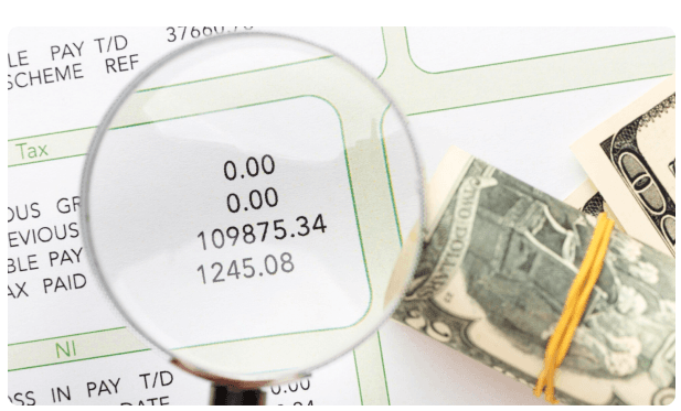 Magnifying glass over a payslip showing tax and net pay figures