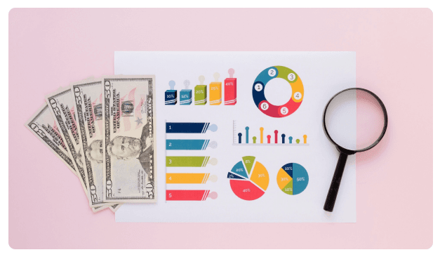 Cash, pie charts, and a magnifying glass laid out on a pink background