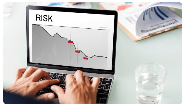 Laptop screen displaying a declining chart labeled 'Risk'