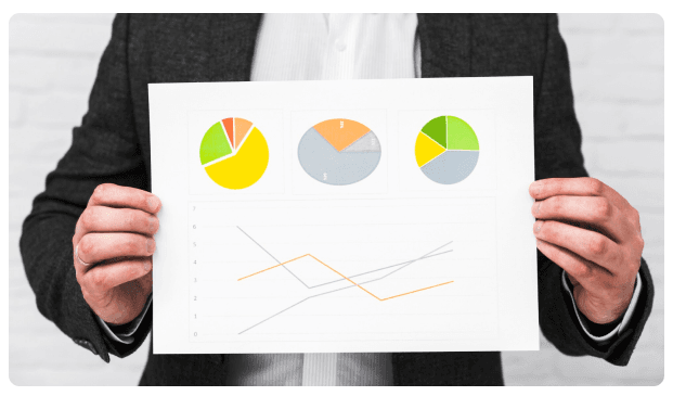 Person holding a document displaying pie charts and line graphs