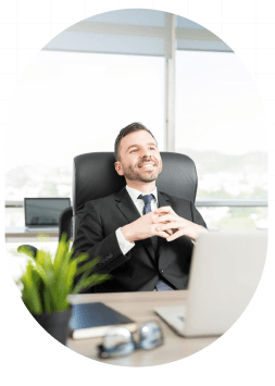Smiling professional relaxing at his desk with a laptop