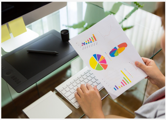Hands reviewing colorful pie charts and bar graphs printed on paper
