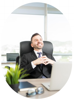 Smiling professional relaxing at his desk with a laptop