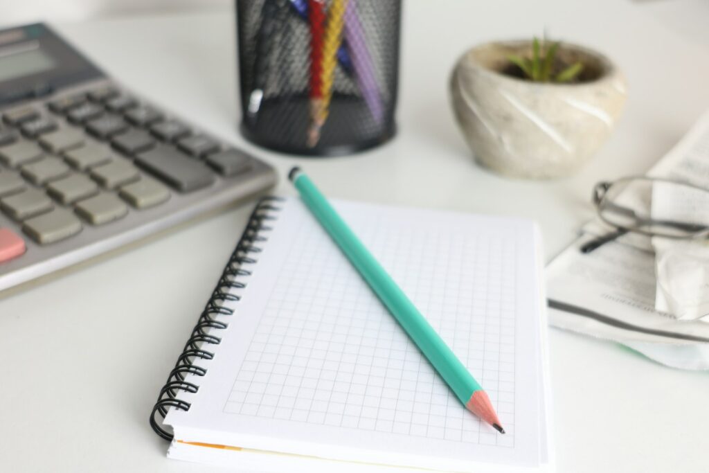 Notebook, calculator and pencil arranged on a desk
