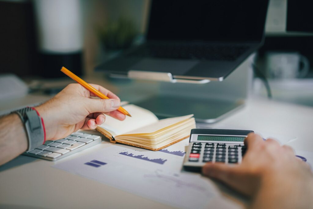 Person using a calculator and notebook at a desk