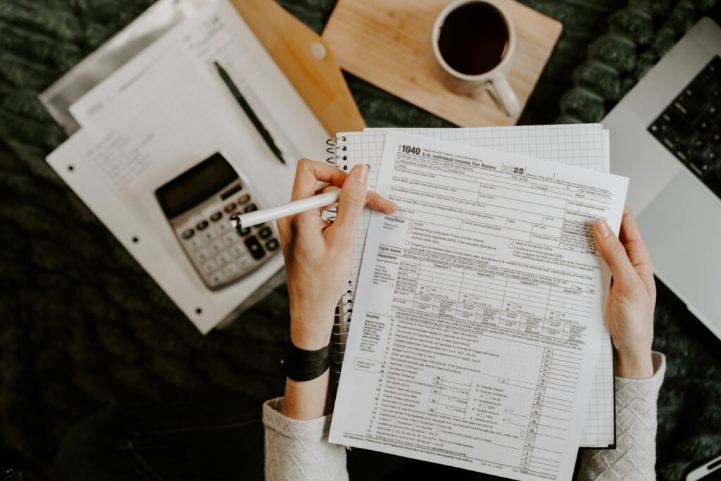 Person reviewing documents with a calculator and laptop