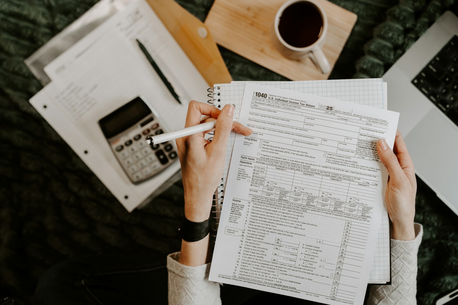 Person reviewing documents with a calculator and laptop